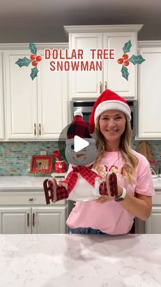 a woman in a santa hat holding up a stuffed animal with the words dollar tree snowman on it