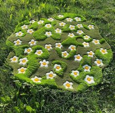 a circular garden design made out of moss with eggs and daisies in the center