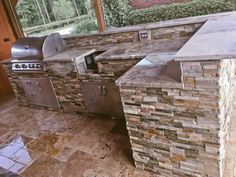 an outdoor kitchen with stone counter tops and grill