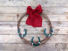 a wreath with two horseshoes and a red bow on the top is sitting on a wooden surface