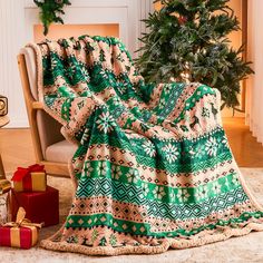 a green and white blanket sitting on top of a chair next to a christmas tree