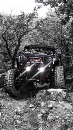 a jeep driving through the rocks on a trail in black and white with bright lights