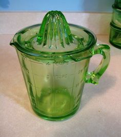 a green blender sitting on top of a counter next to two cups with lids