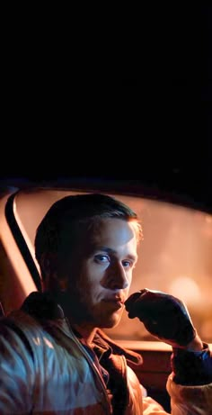 a man sitting in the passenger seat of a car with his hand on his face