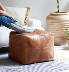 a person sitting on top of a brown ottoman