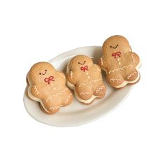 three gingerbreads on a white plate with red bows