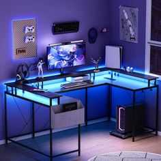 a desk with a computer on it in front of a purple wall and blue lighting