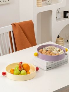 a white table topped with a bowl of fruit