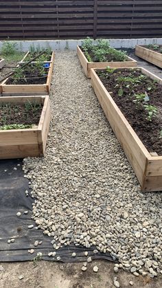 several wooden raised garden beds filled with dirt and rocks on the side of a building