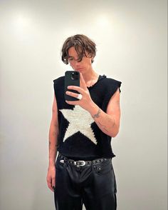 a young man is taking a selfie with his cell phone while wearing leather pants