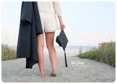 a woman walking on the beach with her graduation cap and gown