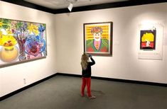 a woman looking at paintings on display in an art gallery