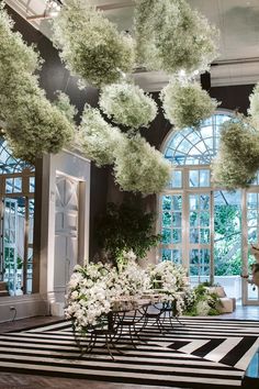 a room filled with lots of windows and white flowers hanging from the ceiling above it