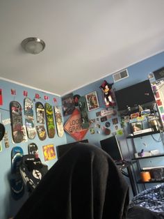 a bedroom with blue walls and lots of skateboards hanging on the wall above it