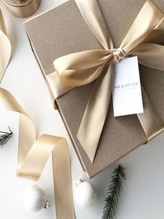 an open gift box wrapped in brown paper and tied with gold ribbon, surrounded by christmas decorations