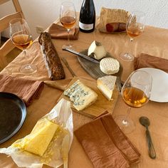 a table with cheese, bread and wine on it is set up for a meal