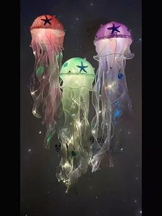 three jellyfish shaped lights hanging from strings in the dark sky with stars on them