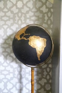 a black and gold globe sitting on top of a wooden stand next to a wall