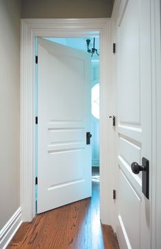 an open door leading to another room with wood floors and white walls, along with a hardwood floor