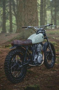 a dirt bike parked in the woods next to a tree