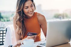 a woman holding a credit card and looking at her laptop