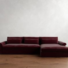 a red couch sitting on top of a hard wood floor next to a white wall