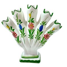 a white vase with flowers painted on it's sides and green trim around the edges