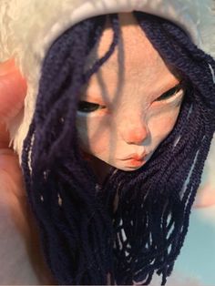 a close up of a person holding a doll with purple dreadlocks on it's head