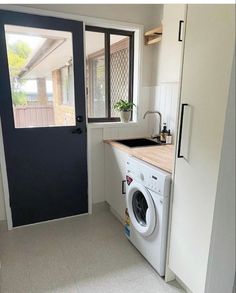 a washer and dryer in a small room with an open door to the outside