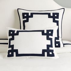 two black and white pillows sitting on top of a bed next to eachother