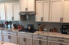 a kitchen with white cabinets and granite counter tops