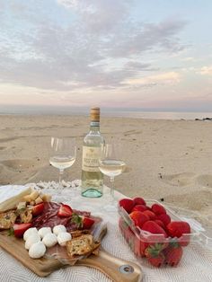 two glasses of wine, strawberries and crackers on the beach