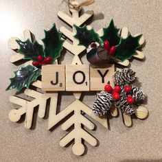 a christmas ornament made out of wooden letters and pine cones