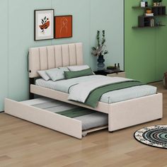 a bed sitting on top of a hard wood floor next to a green painted wall