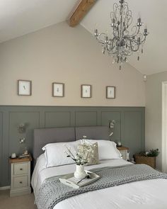 a bedroom with a bed, chandelier and pictures on the wall above it