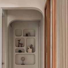 a bathroom with white walls and shelves filled with vases