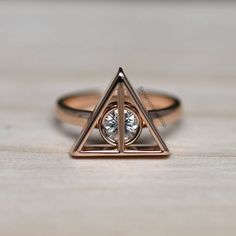 a gold ring with a triangle and a diamond in the middle on a wooden surface