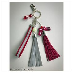 three tassels are attached to a keychain on a white table top