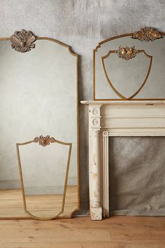 two mirrors sitting next to each other on top of a wooden floor in front of a fireplace