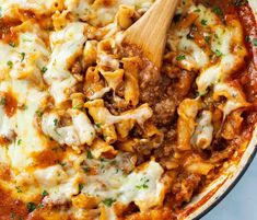 a skillet filled with pasta and meat covered in sauce, cheese and parsley