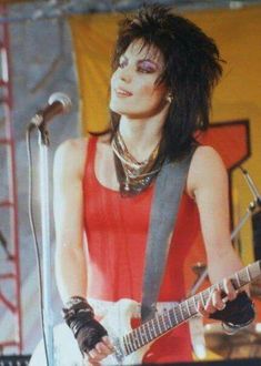 a woman in red shirt playing guitar on stage