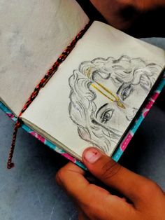 a person holding an open book with a drawing on it