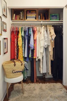 an organized closet with clothes hanging on the wall, and a bench in front of it