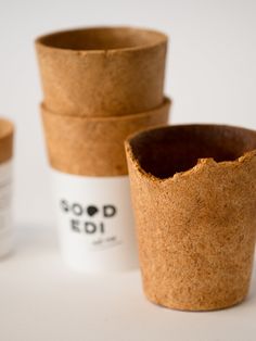 three small cups sitting next to each other on top of a white table with the words good edi printed on them