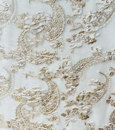 white and gold brocaded fabric with large flowers on it's side, closeup