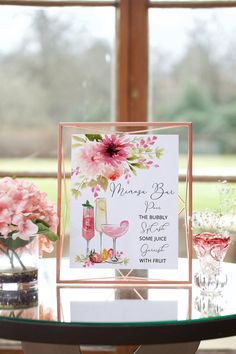 a table topped with pink flowers and wine glasses next to a sign that says please bar