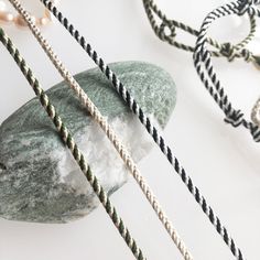 several ropes and pearls are tied together on a rock next to a pearl bead necklace