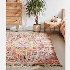 a room with a bed, dresser and rug on the floor in front of it