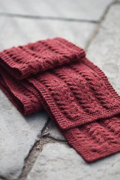 a red knitted scarf laying on the ground