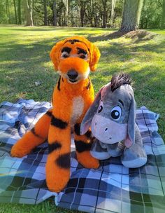 two stuffed animals sitting on a blanket in the grass